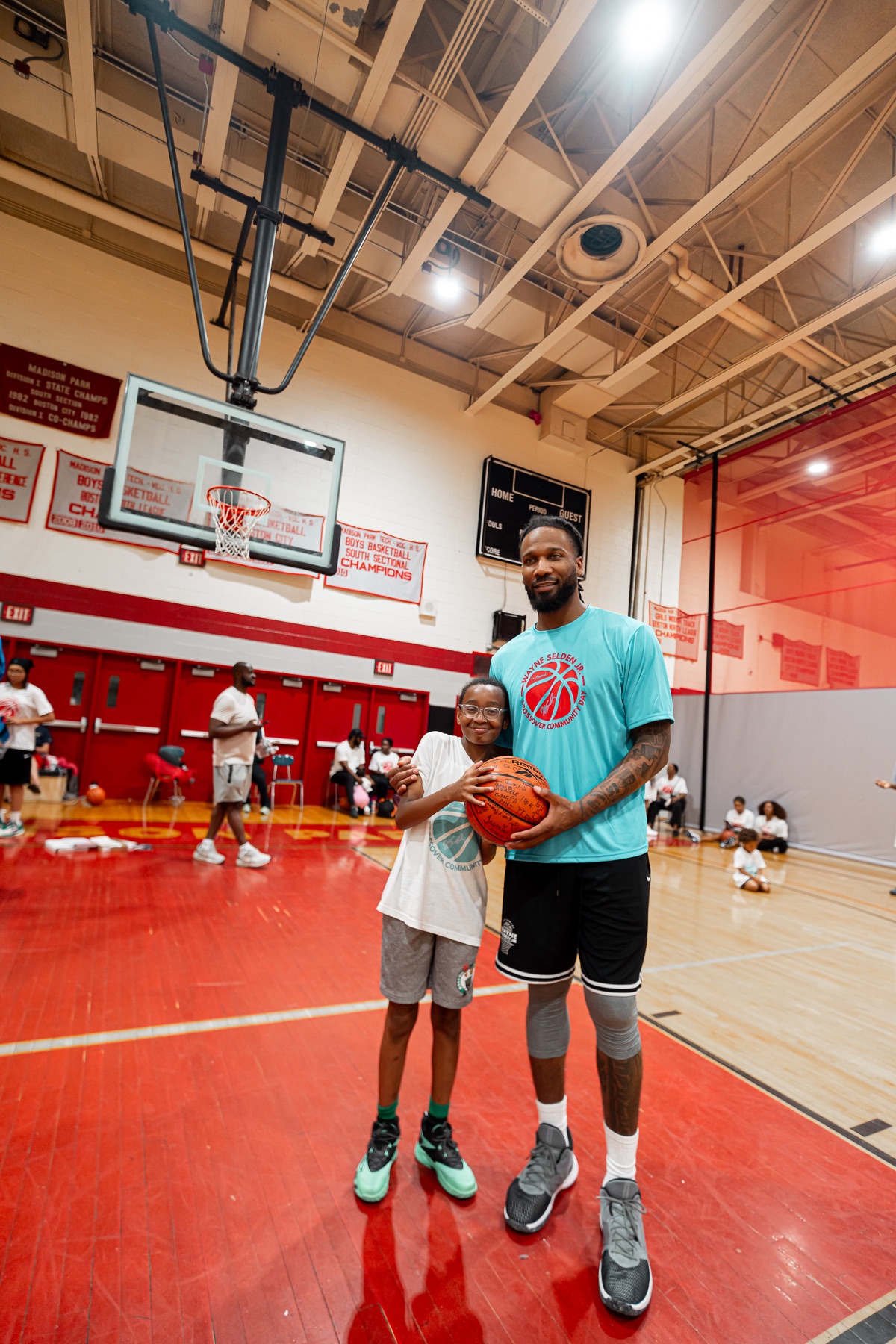 Wayne Selden Jr. standing with a young participant holding a basketball